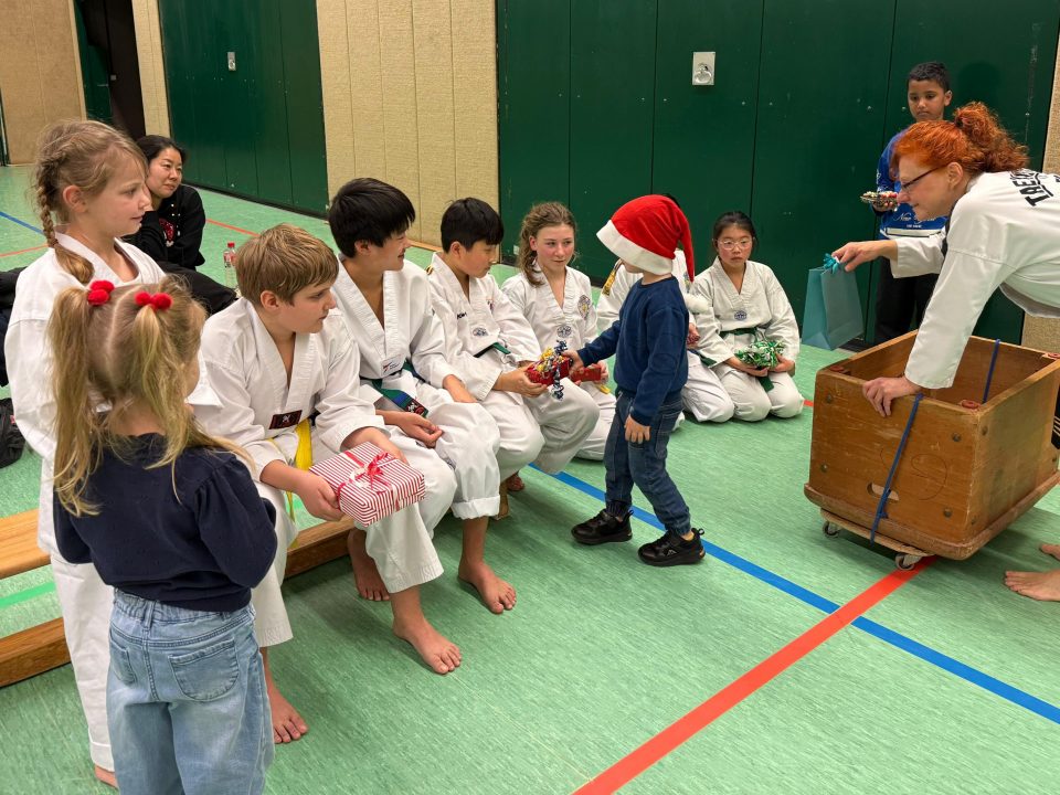 Ein kleiner Weihnachtsmann verteilt Geschenke an die Taekwon-Do-Kinder